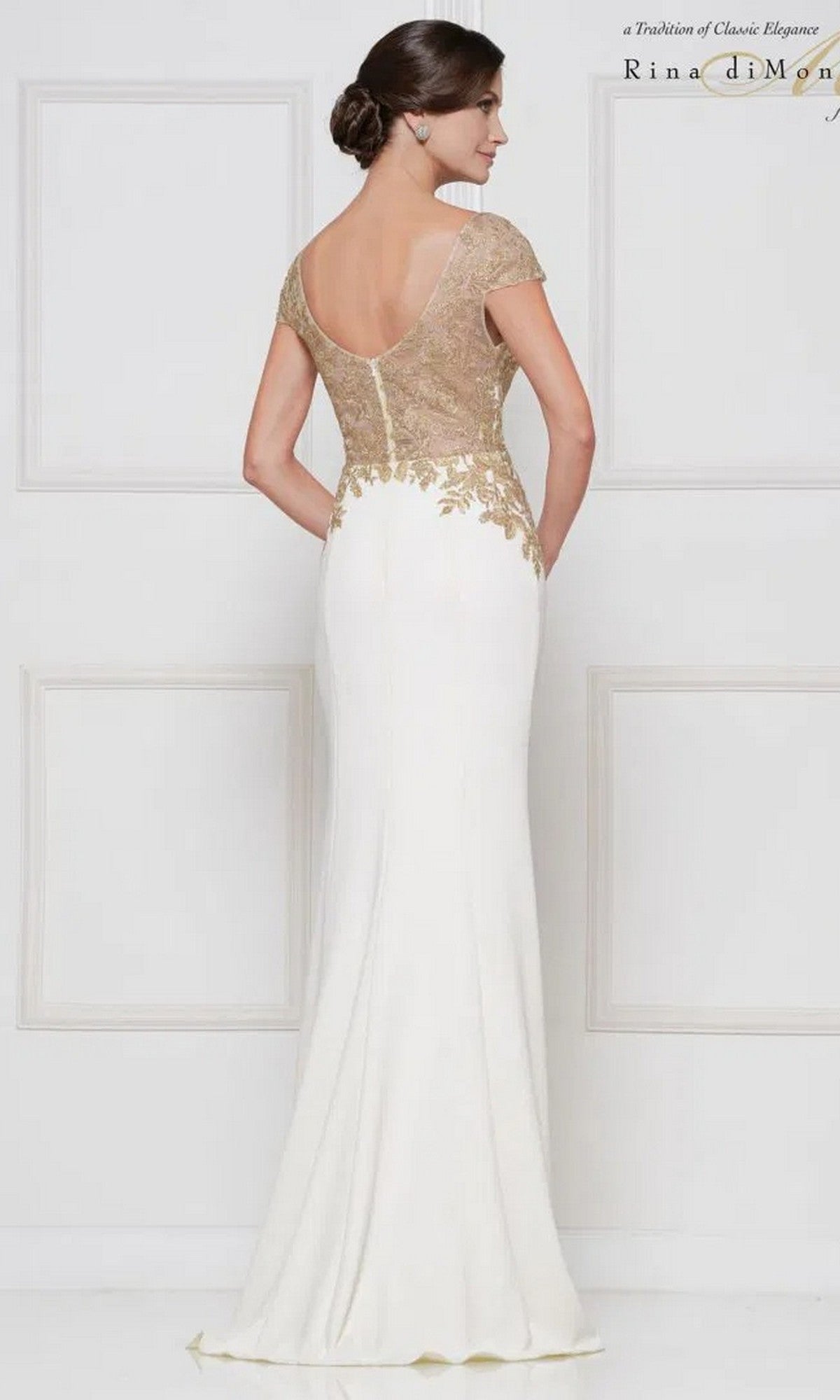 A woman is shown from the back against a plain white background wearing the Rina Di Montella RD2652, a floor-length white formal dress with gold-embroidered bodice, cap sleeves, and a sheath skirt.